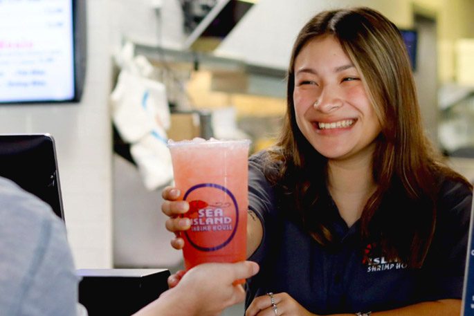 A young woman serving strawberry lemonade to a customer at Sea Island Shrimp House